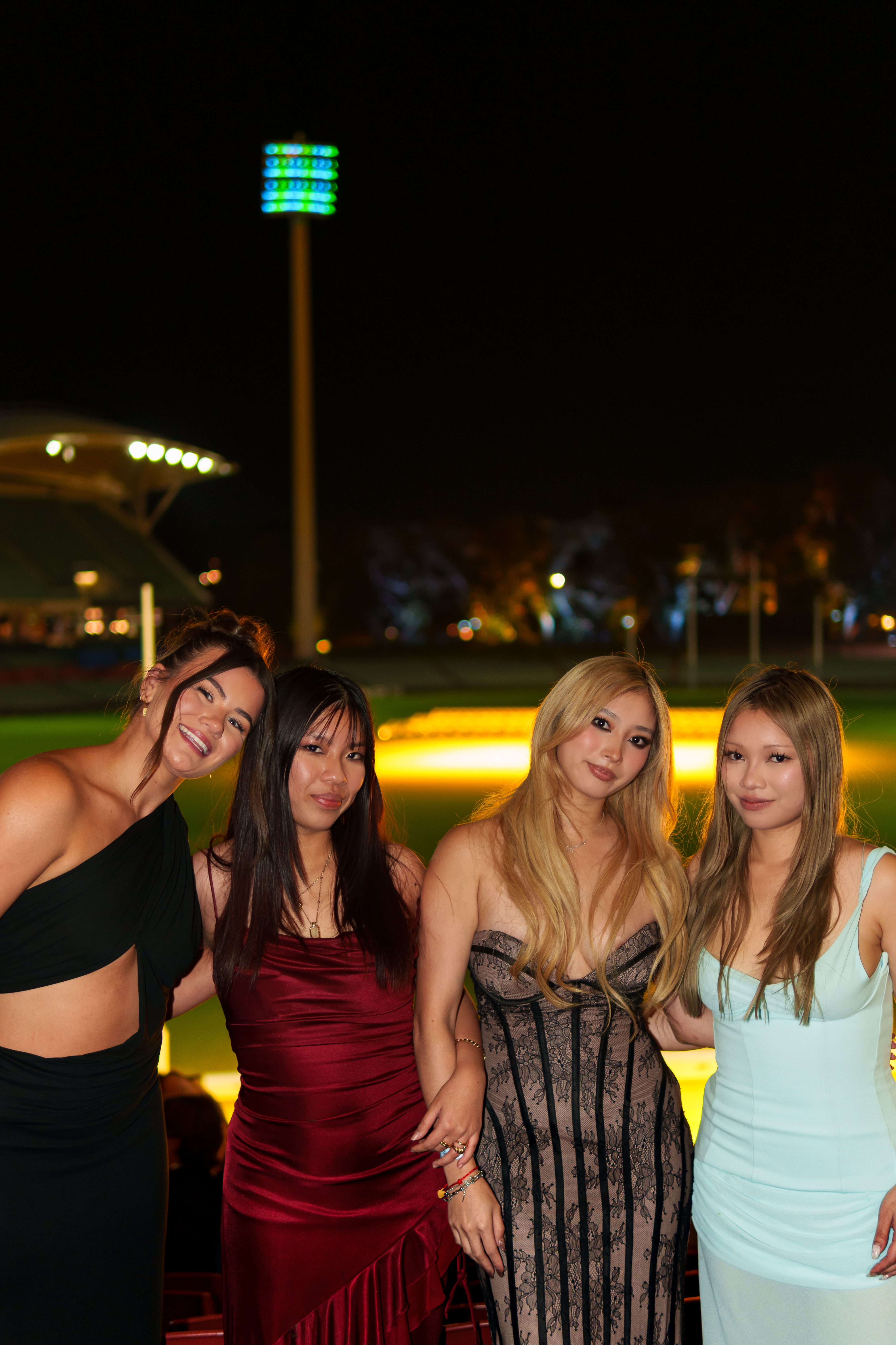 Four guests posing together at an outdoor evening event